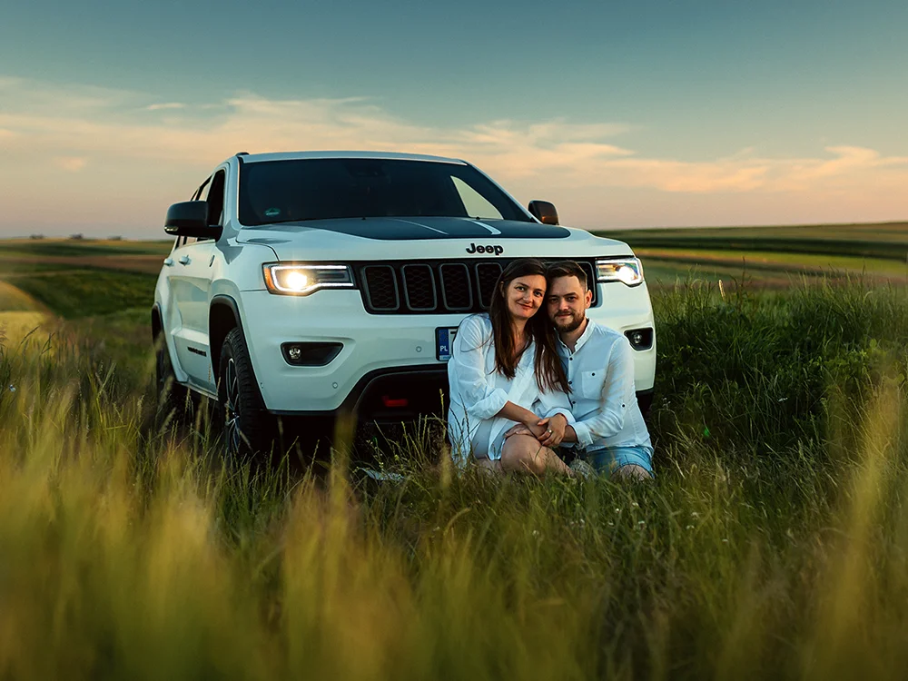 Plenerowa sesja ciążowa pary z Jeepem Grand Cherokee wśród malowniczych pól w Sułoszowej