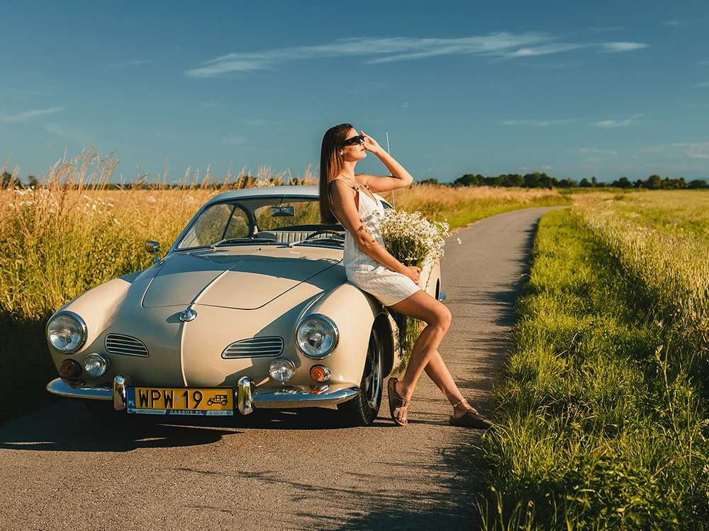 Letnia sesja retro Volkswagen Karmann Ghia z 1960 roku z modelką na drodze wśród pól w okolicach Brzeska